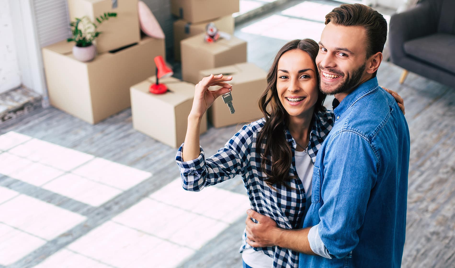 A young couple happily holding keys to their new home