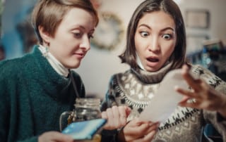 Two women looking at a receipt, shocked because of inflation