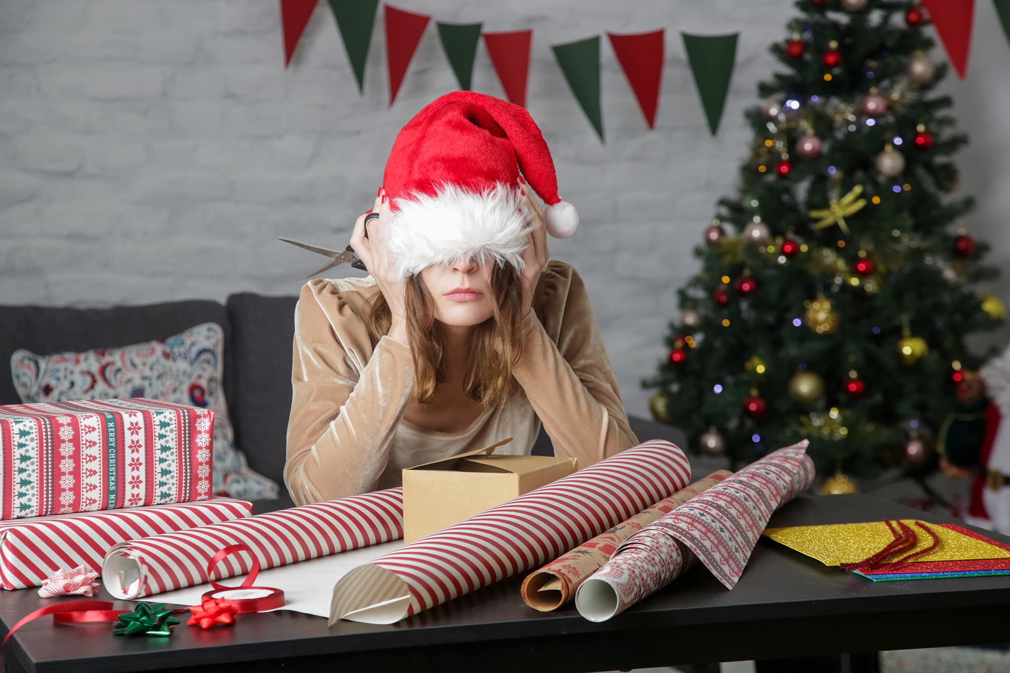 Depressed frustrated woman wrapping Christmas gift boxes, winter holiday stress concept