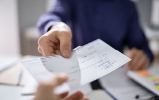 Businessperson Hands Giving Check To Other Person